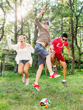 Tre ungdomar hoppar på en gräsmatta.