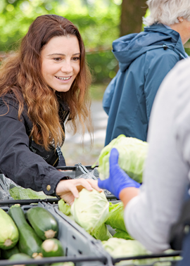 En kvinna köper grönsaker på Bondens marknad i Umeå.