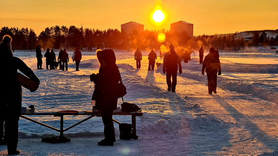 Människor som går och åker på isvägen i Lycksele i solnedgång