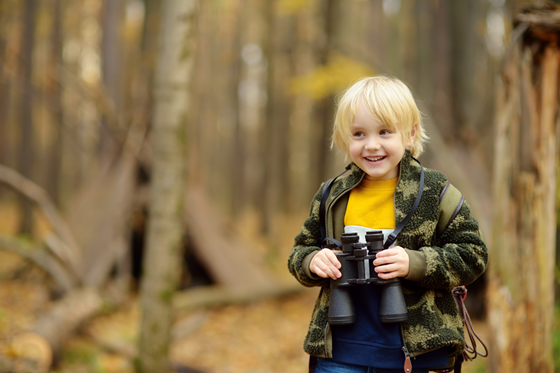 Barn med kikare i skog