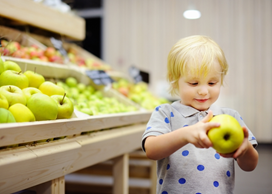 En liten pojke med ett äpple i händerna