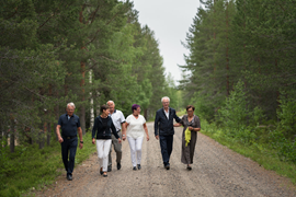 Sex personer som går på en skogsväg