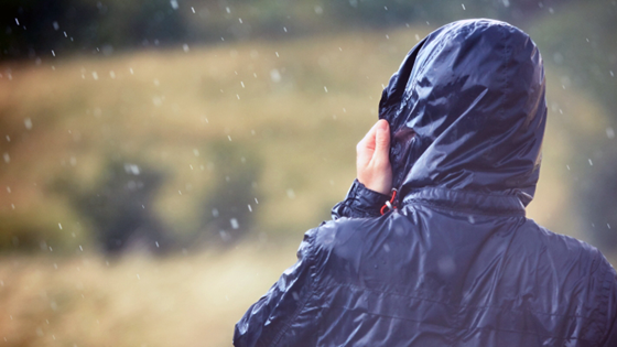 En person i regnkläder värjer sig mot kraftigt regn..