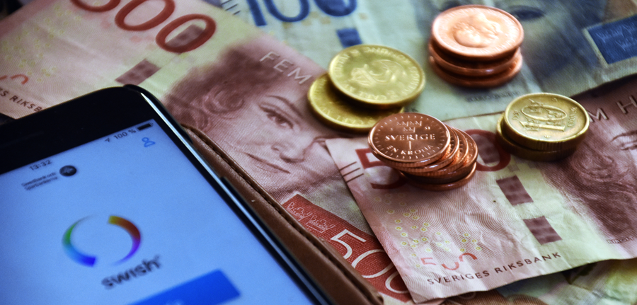 Bild på sedlar och mynt samt en mobiltelefon med appen Swish öppen