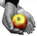 En mans hand och en kvinnas hand håller tillsammans ett röd/gult äpple