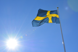 Bild på Svenska flaggan med blå himmel som bakgrund