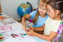Bild på två barn som pysslar med färger och pennor.