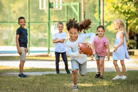 Bild på barn som springer utomhus med en boll.