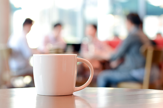 Bild på en kaffekopp med människor som pratar i bakgrunden