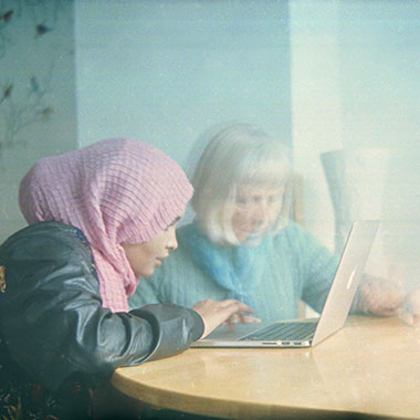 Två personer, en äldre och en yngre som tittar i en dator.
