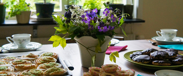 Bullar, kakor, kaffekoppar och blommor på bord, foto.